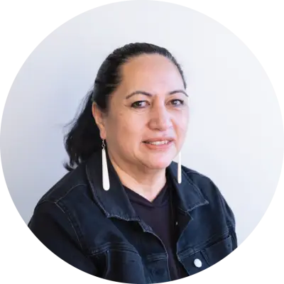 Georgina is a Māori woman. She has her long, dark hair pulled back in a pony tail. .