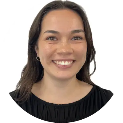 Ruby is a young woman facing forward, wearing small hoop earrings and a black top with a round neckline. . 