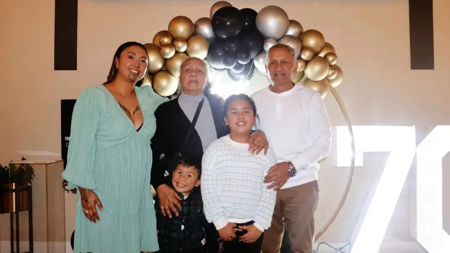 Te Uranga Pihama stands with an older man and woman and two children in front of a balloon arch. .
