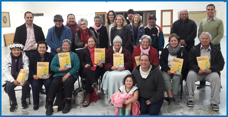 Group of people in a hall holding copies of the Pacific Responsive Strategy. . 